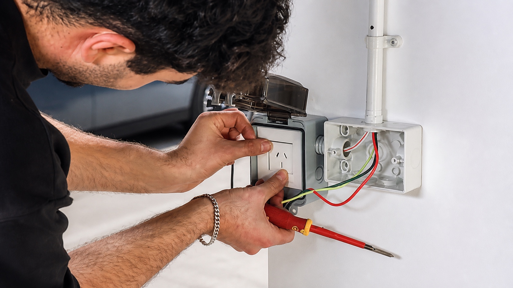 Installer fitting an Australian weatherproof outlet during a car park retrofit